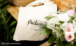 Panachage de sacs tote bag.
Visuel : ' Logo Pacheco, artisan fleuriste en noir. Photo du sac avec un bouquet de fleurs roses et blanches par dessus'.